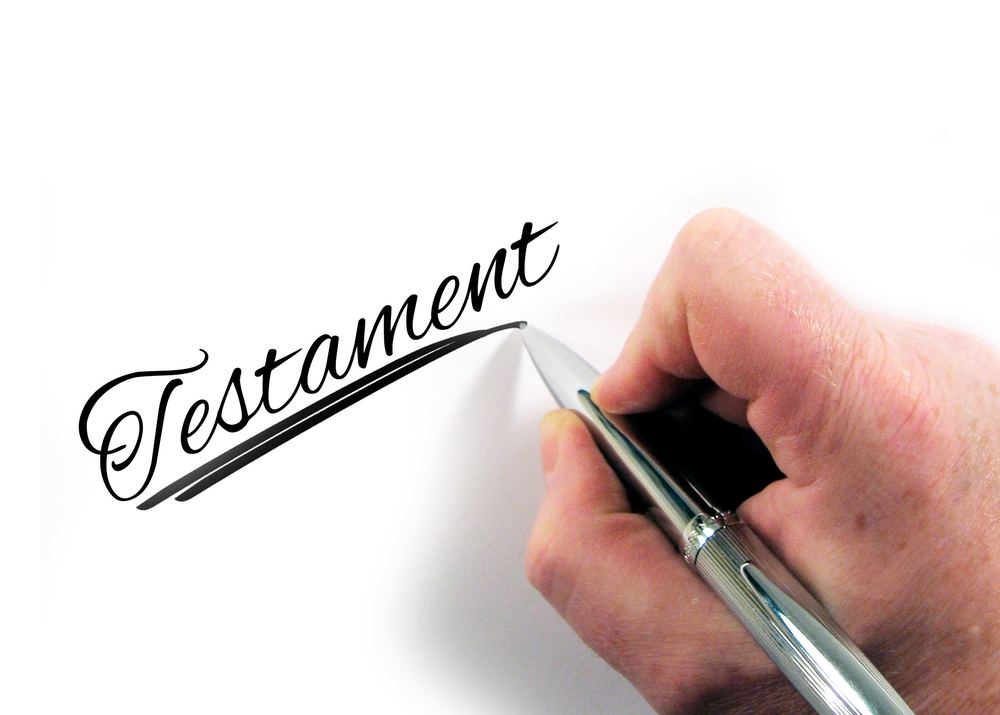 Mão escrevendo a palavra Testamento em caligrafia, representando a formalização de um testamento