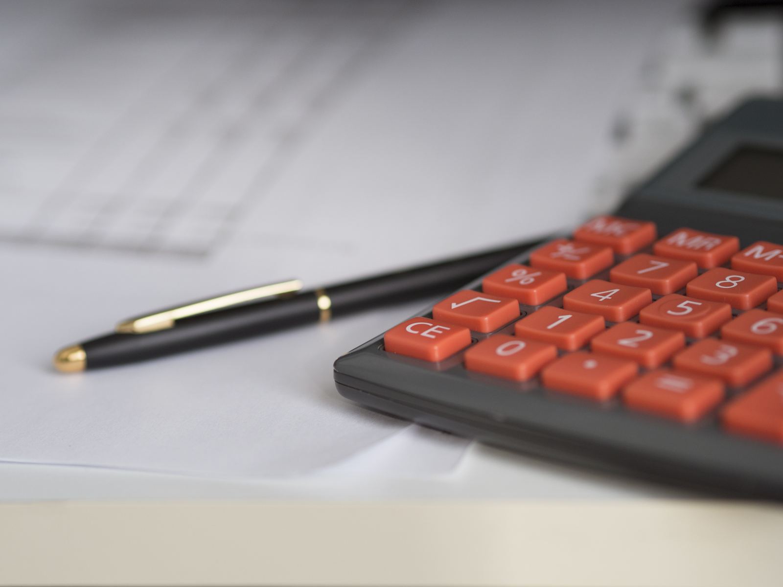 Calculadora e caneta sobre documentos, representando o cálculo da pensão alimentícia
